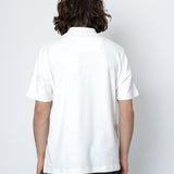 Person wearing a white polo shirt and dark pants on a white background