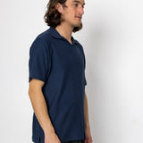 Man wearing a navy blue polo shirt against a white background