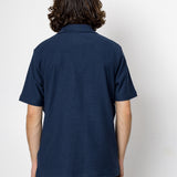 Person wearing a navy blue polo shirt against a white background