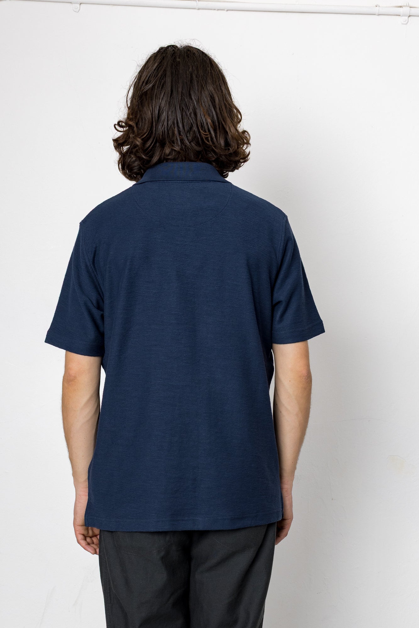 Person wearing a navy blue polo shirt against a white background