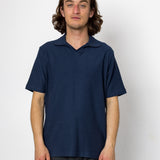 Man wearing a navy blue polo shirt against a white background