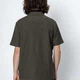 Person wearing a dark green polo shirt against a white background