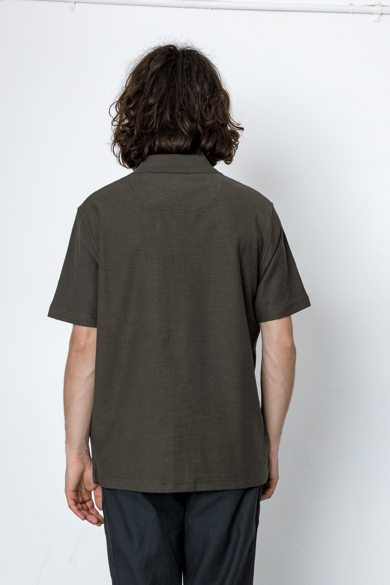 Person wearing a dark green polo shirt against a white background