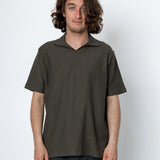 Man wearing a dark green polo shirt against a white background