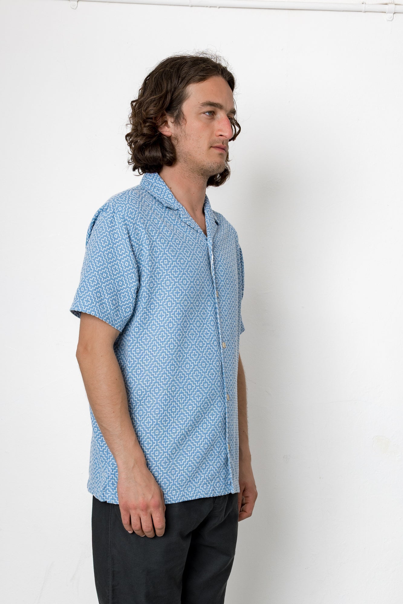 Man wearing a blue patterned shirt against a white background