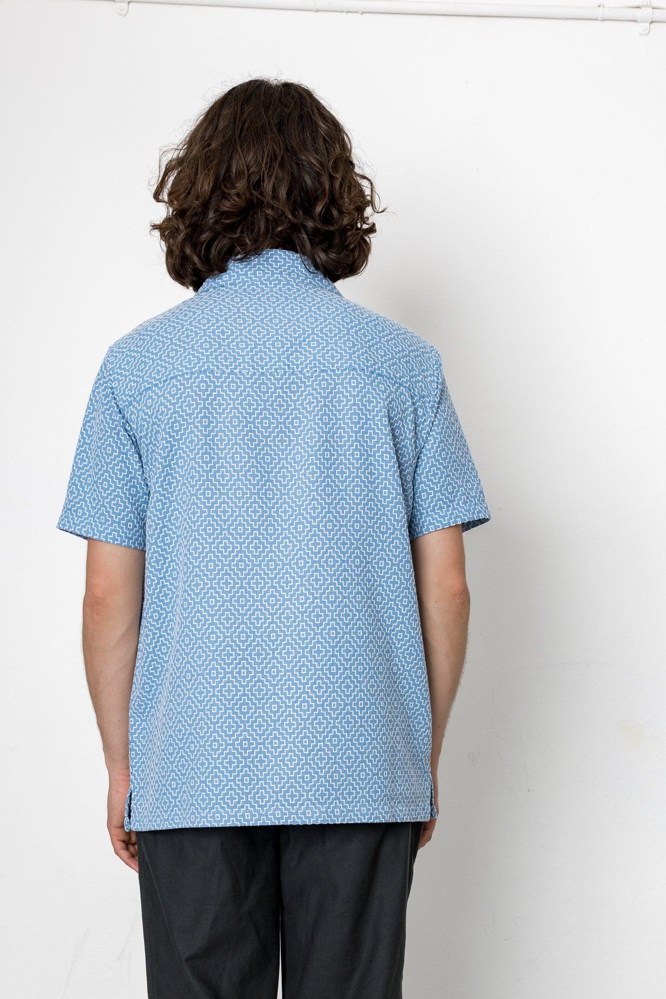 Person wearing a blue patterned shirt against a white background
