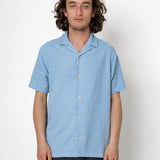 Man wearing a blue patterned shirt against a white background