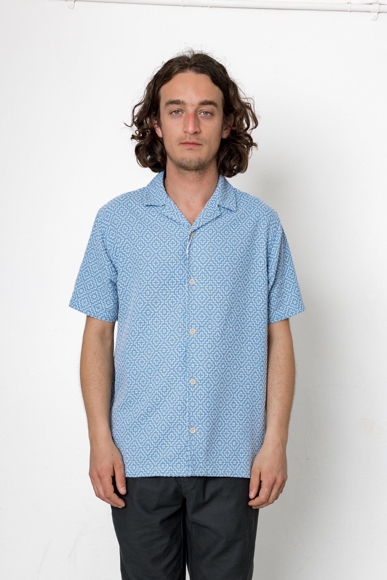 Man wearing a blue patterned shirt against a white background