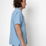 Man wearing a blue patterned shirt against a white background