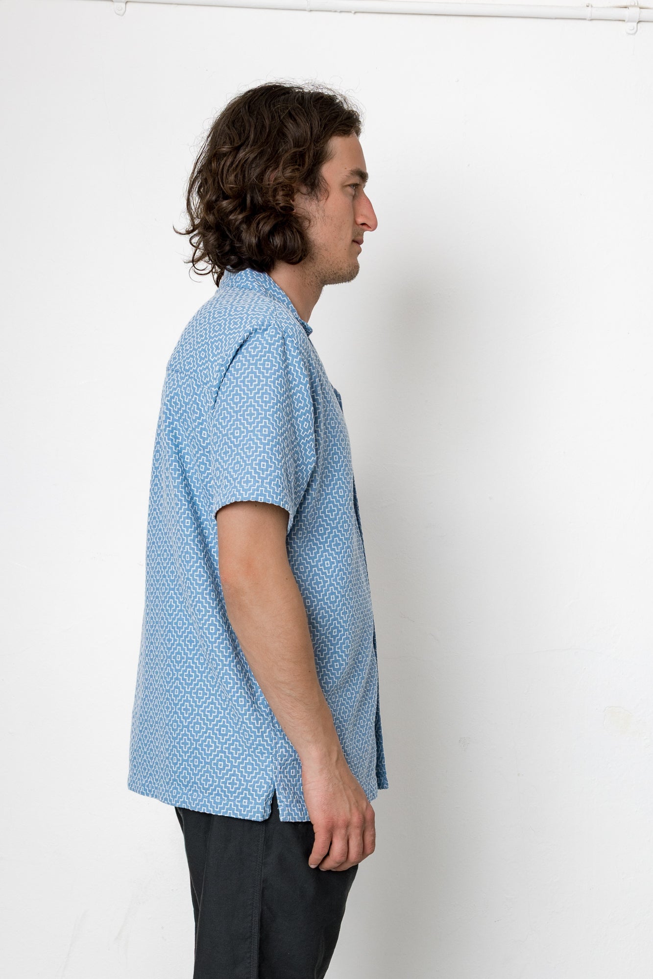 Man wearing a blue patterned shirt against a white background