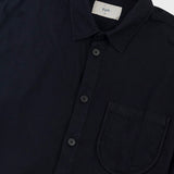 Close-up of a dark navy button-up shirt with a collar, chest pocket, and a visible Folk label inside the neck, shot against a light gray background.