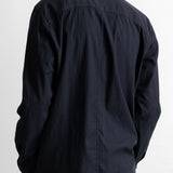 A man viewed from behind wearing a black long-sleeve button-down shirt with a subtle vertical textured stripe pattern.