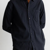A man wearing a black long-sleeve button-down shirt with a chest pocket, shown from the chin down against a plain light background.