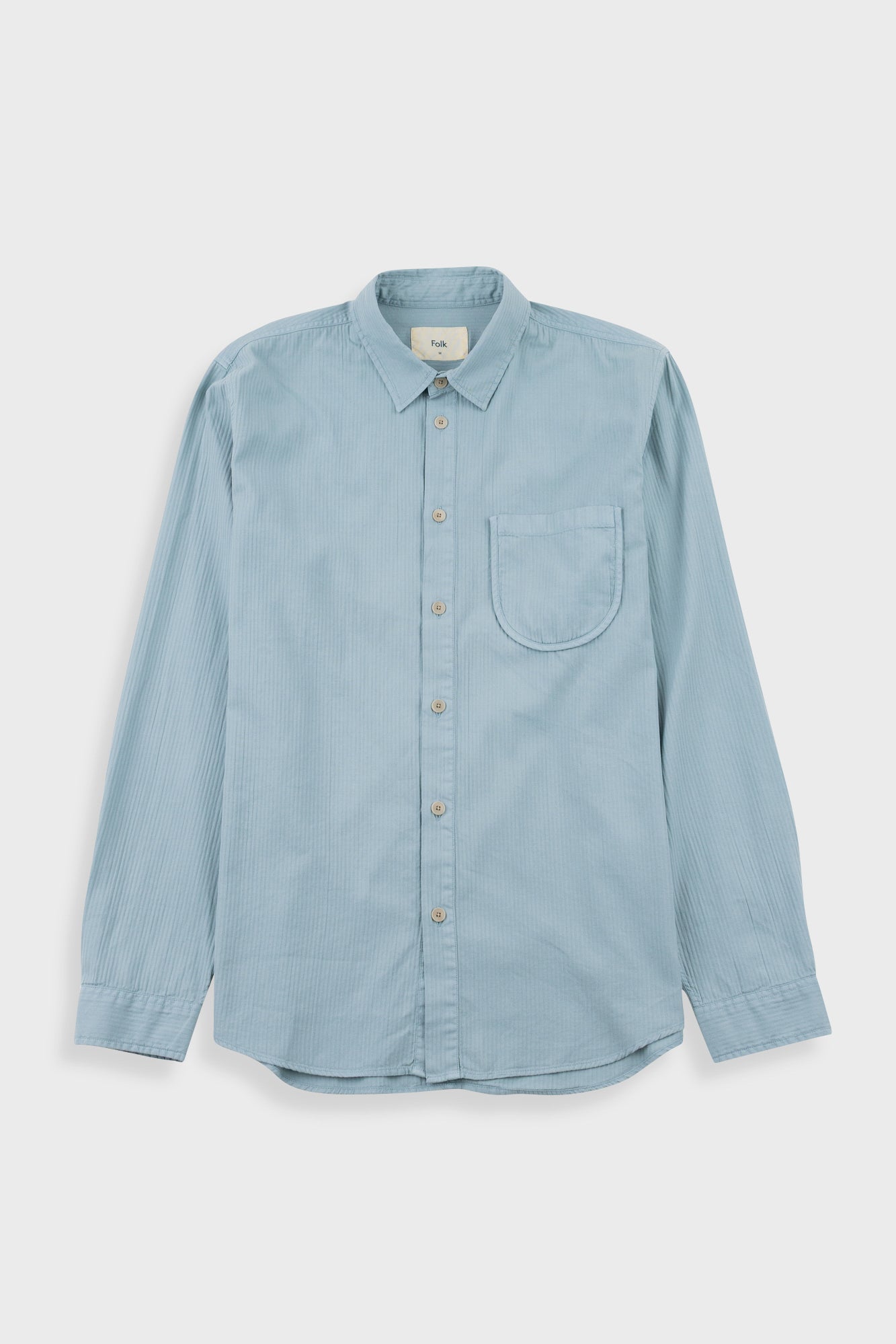A light blue long-sleeve button-up shirt with a single chest pocket, laid flat against a light gray background.