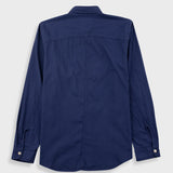 A navy blue long-sleeve button-up shirt shown from the back, featuring a collar, a vertical center back seam, and buttoned cuffs, displayed on a light gray background.