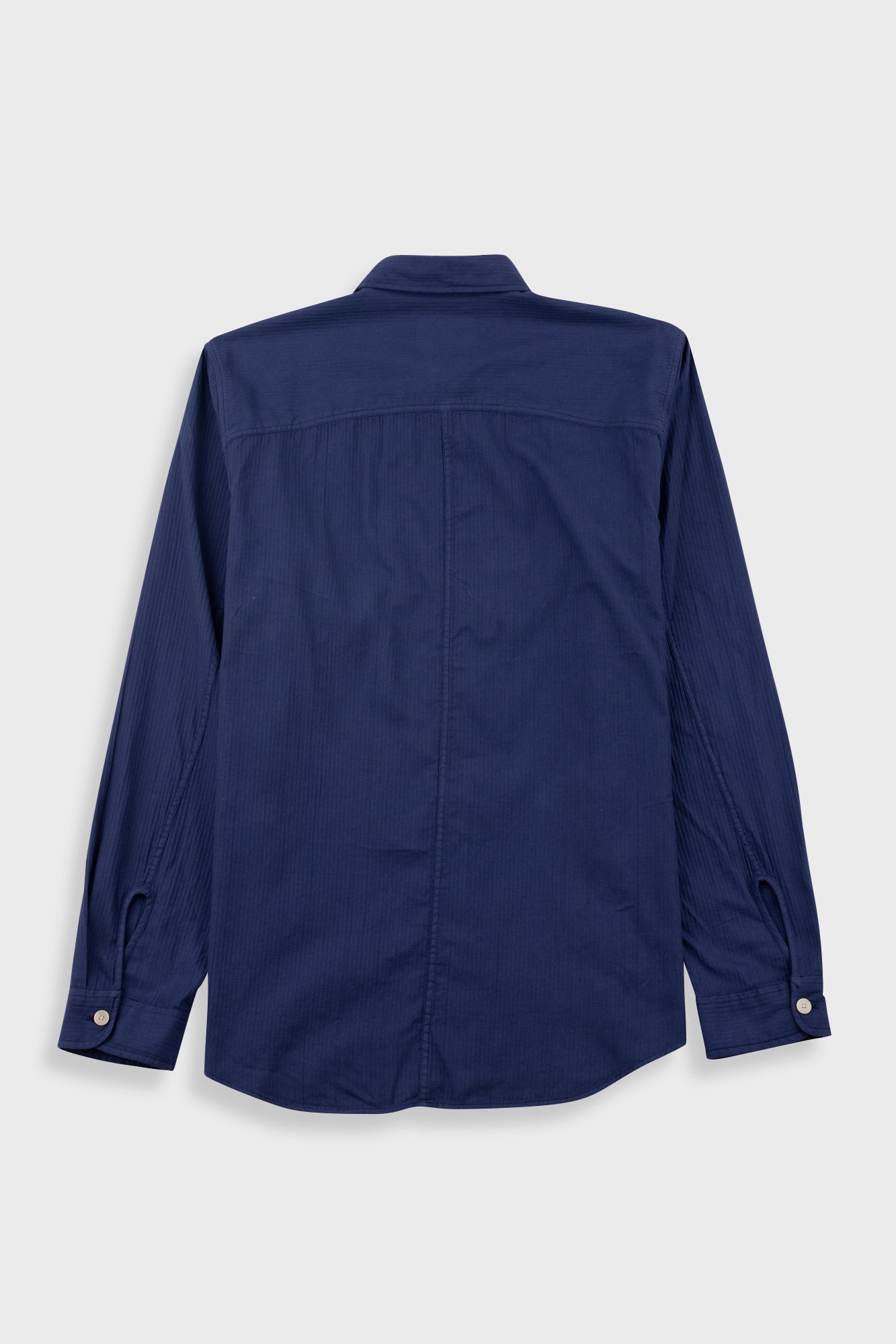 A navy blue long-sleeve button-up shirt shown from the back, featuring a collar, a vertical center back seam, and buttoned cuffs, displayed on a light gray background.