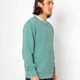 Man wearing a teal sweater against a white background