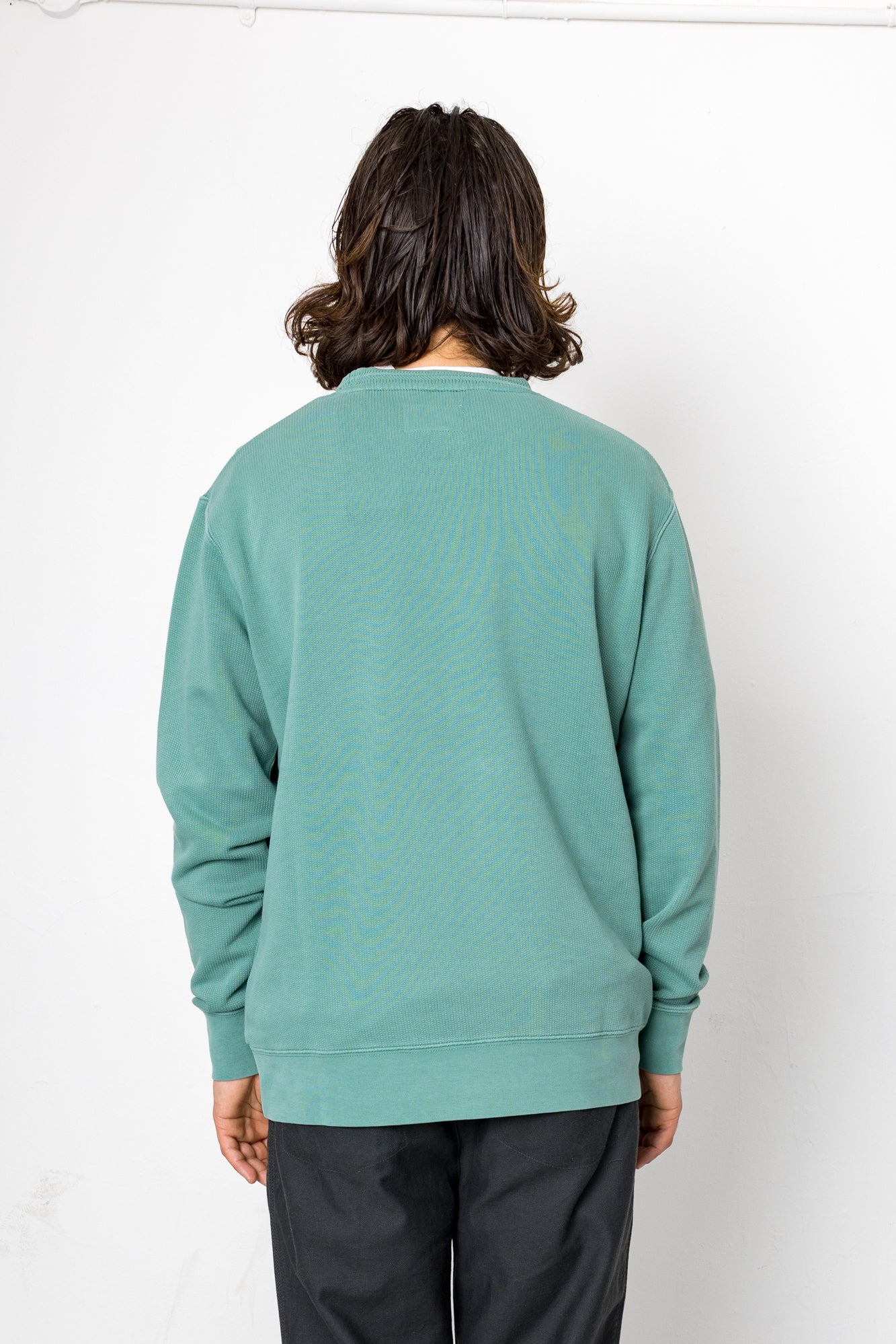 Person wearing a teal sweatshirt against a white background