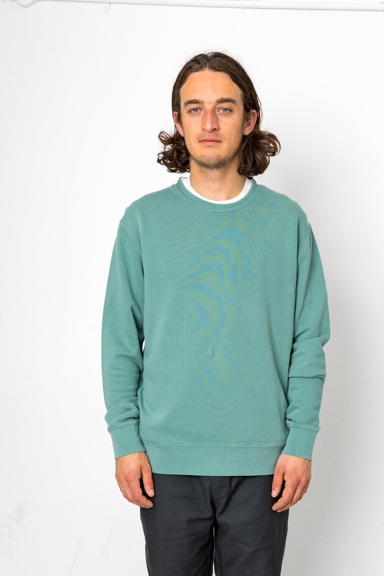 Person wearing a teal sweater with a white background
