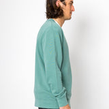 Person wearing a teal sweater against a white background