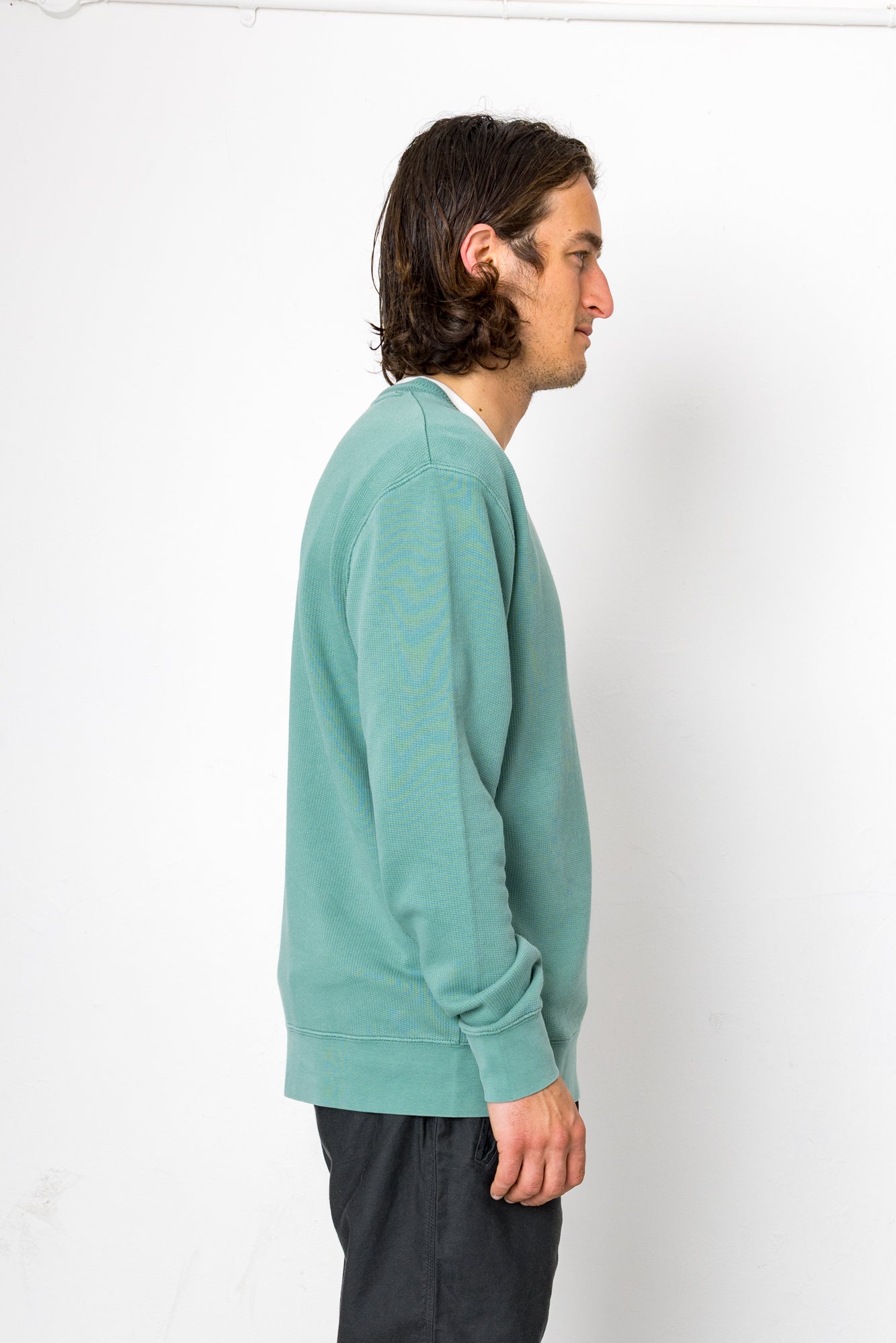 Person wearing a teal sweater against a white background