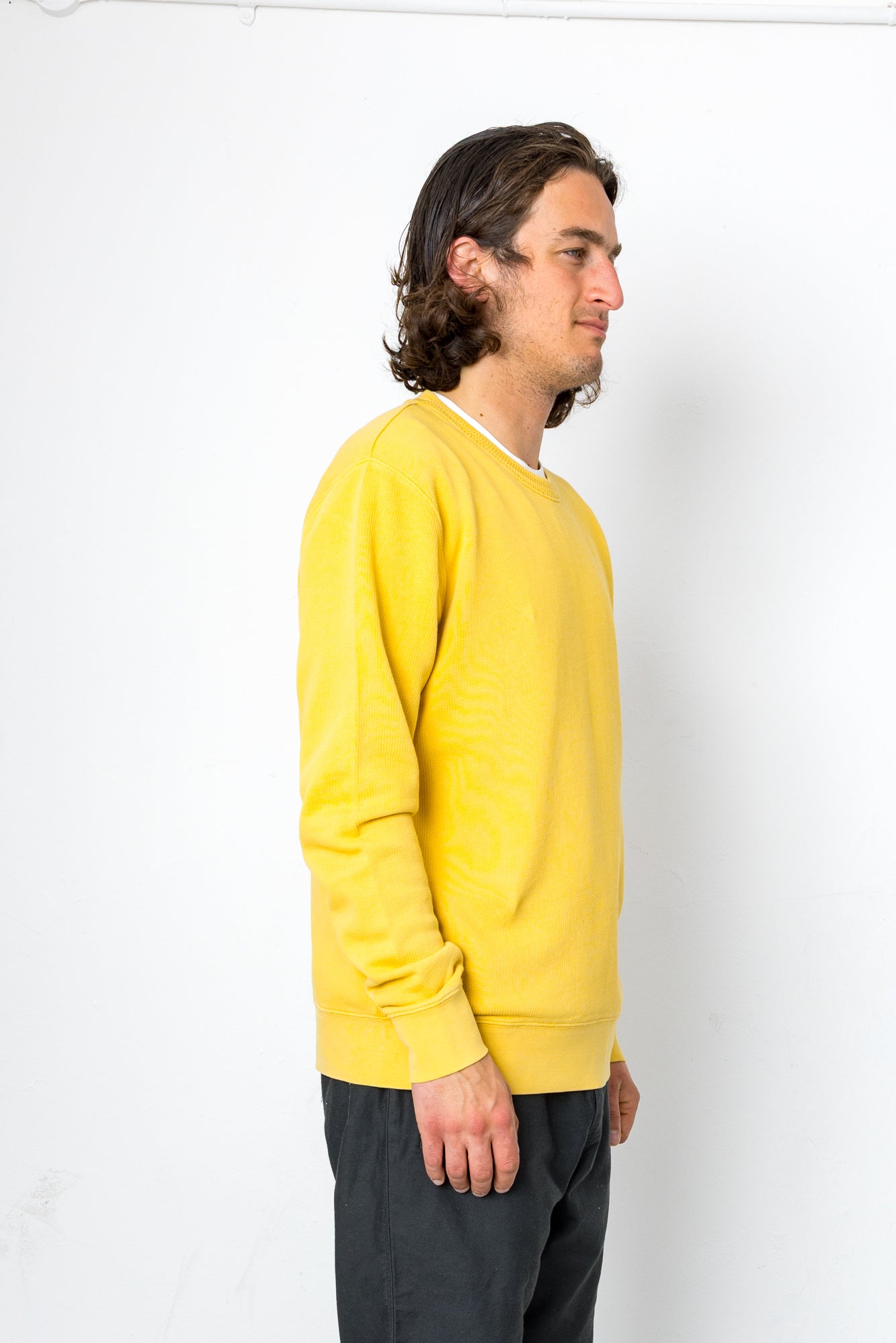 Person wearing a yellow sweater against a white background