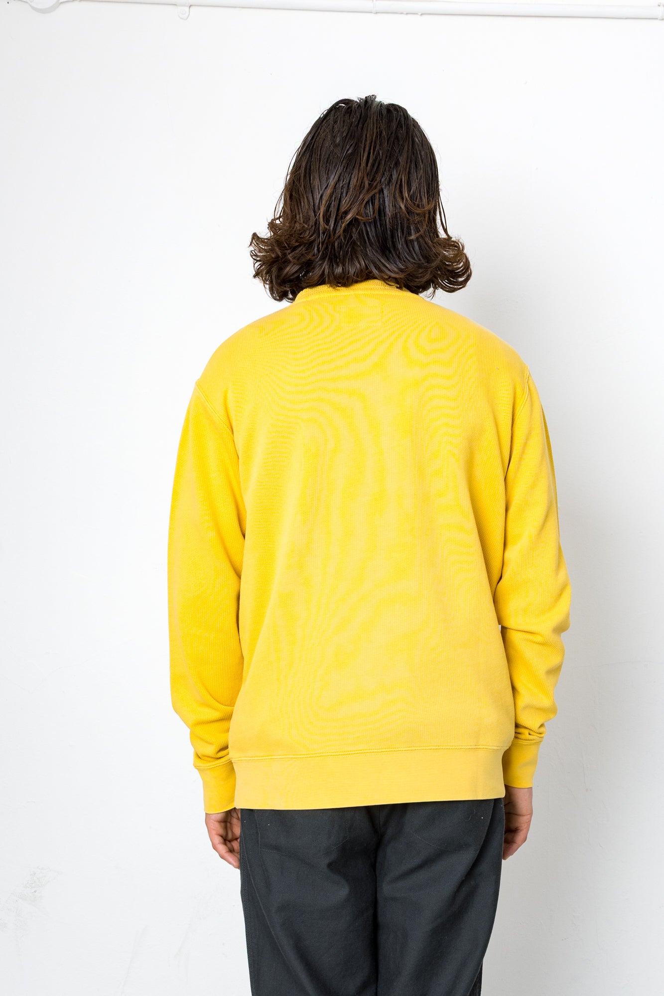 Person wearing a yellow sweater with a white background