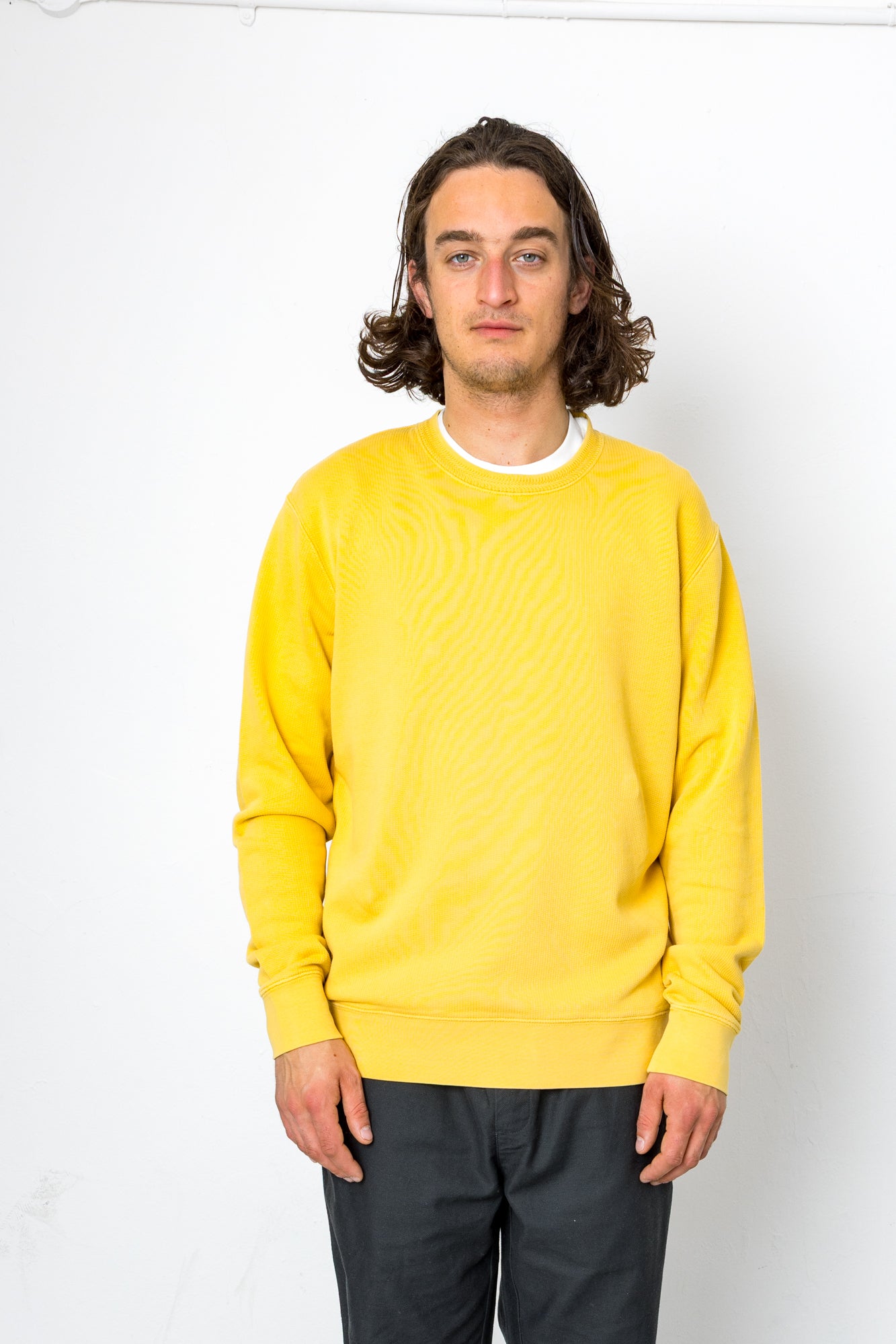 Person wearing a yellow sweatshirt against a white background