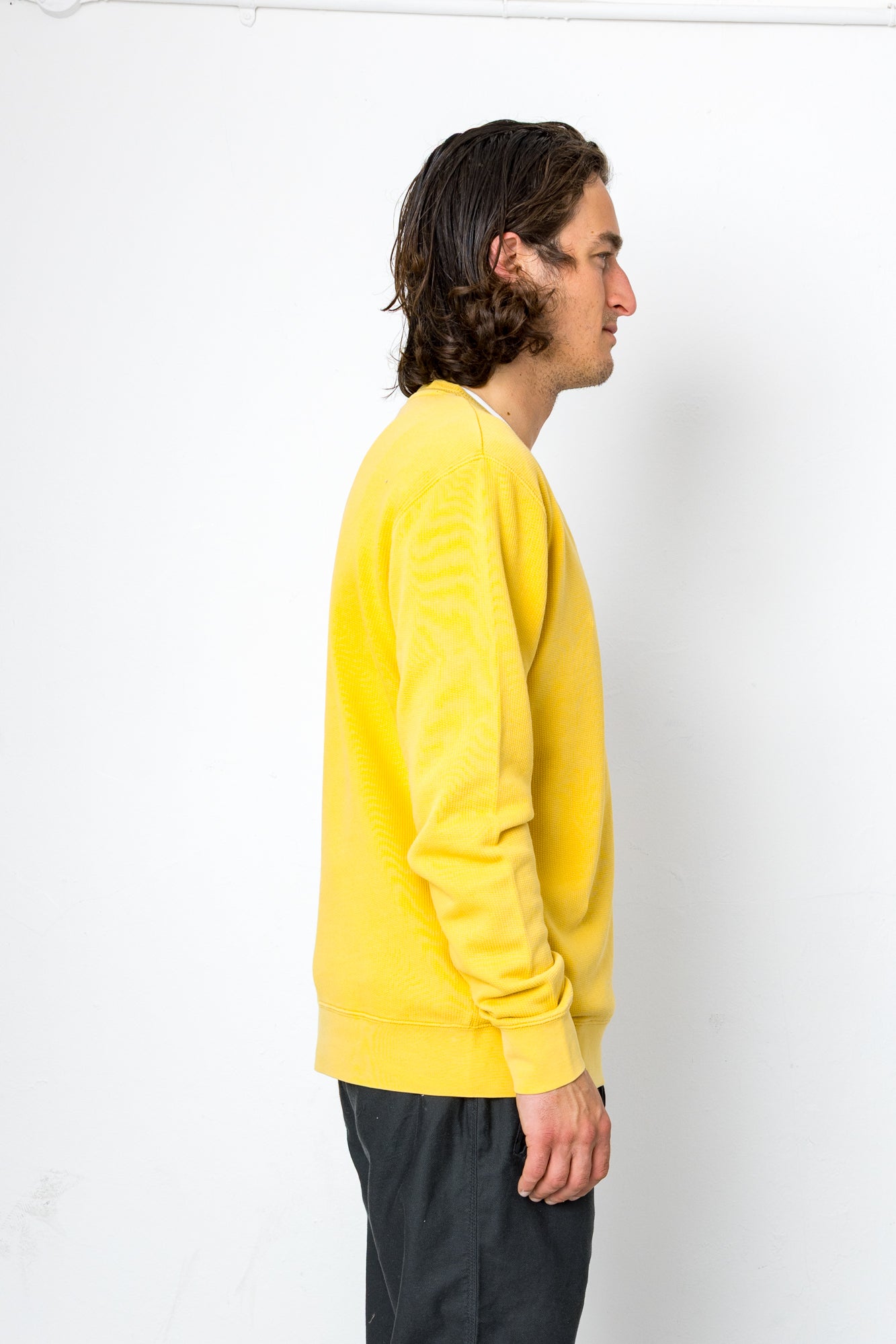 Person wearing a yellow sweater standing against a white background