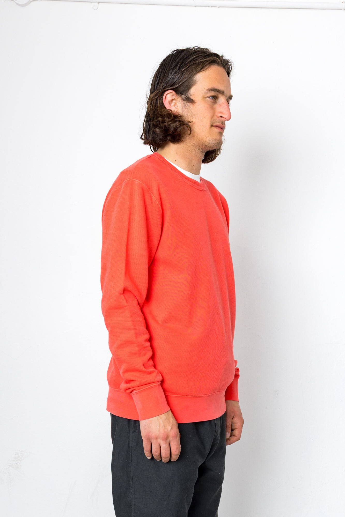 Person wearing a bright orange sweatshirt against a white background
