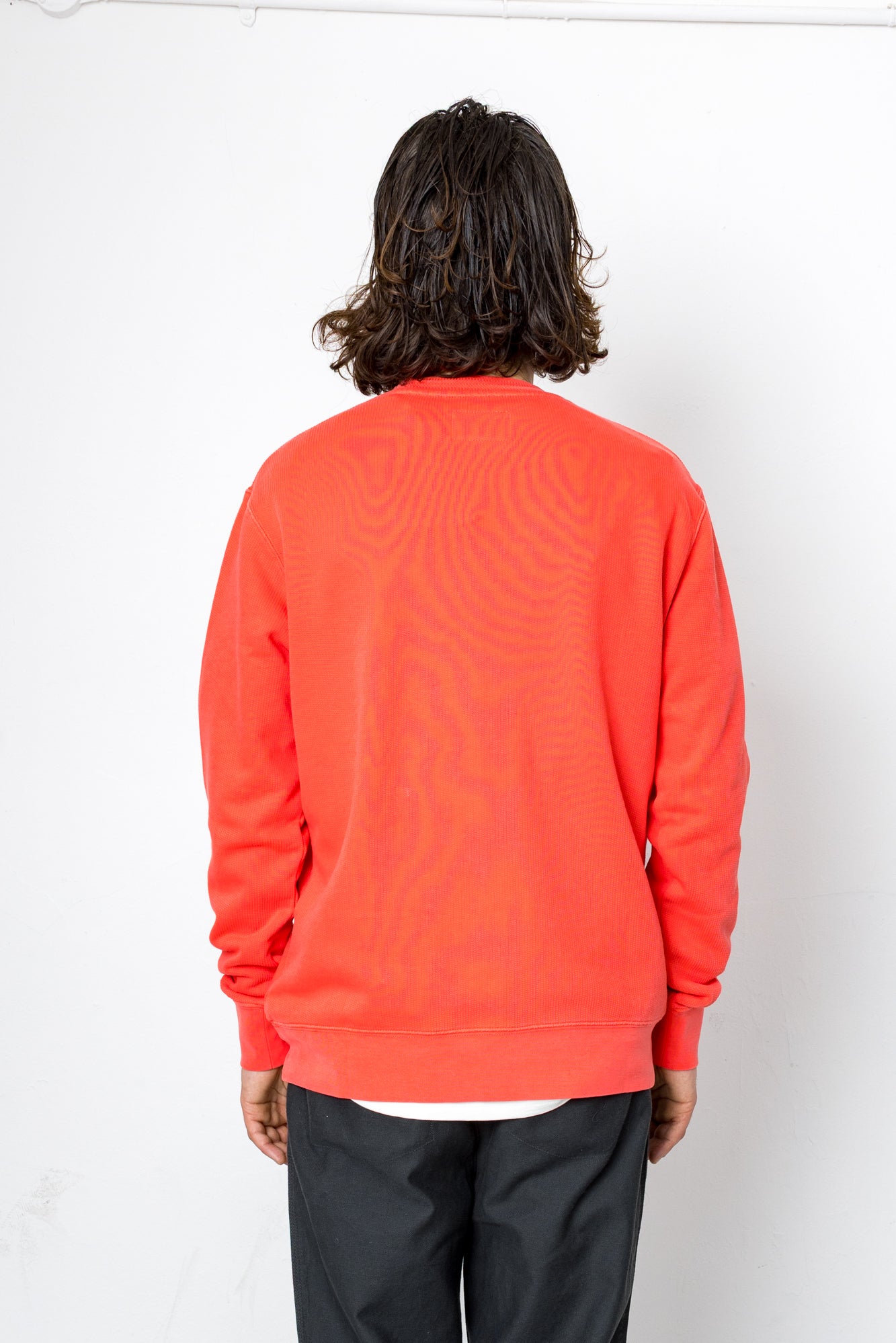 Person wearing a bright orange sweatshirt with a white background