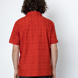 Person wearing a red shirt and black pants against a white background