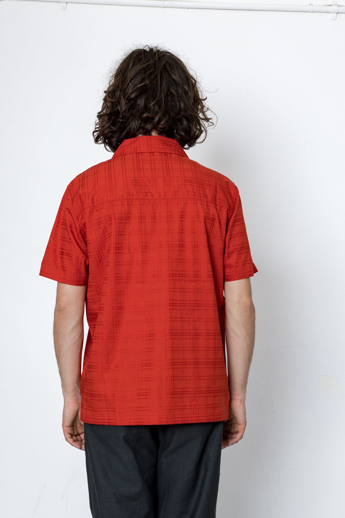 Person wearing a red shirt and black pants against a white background