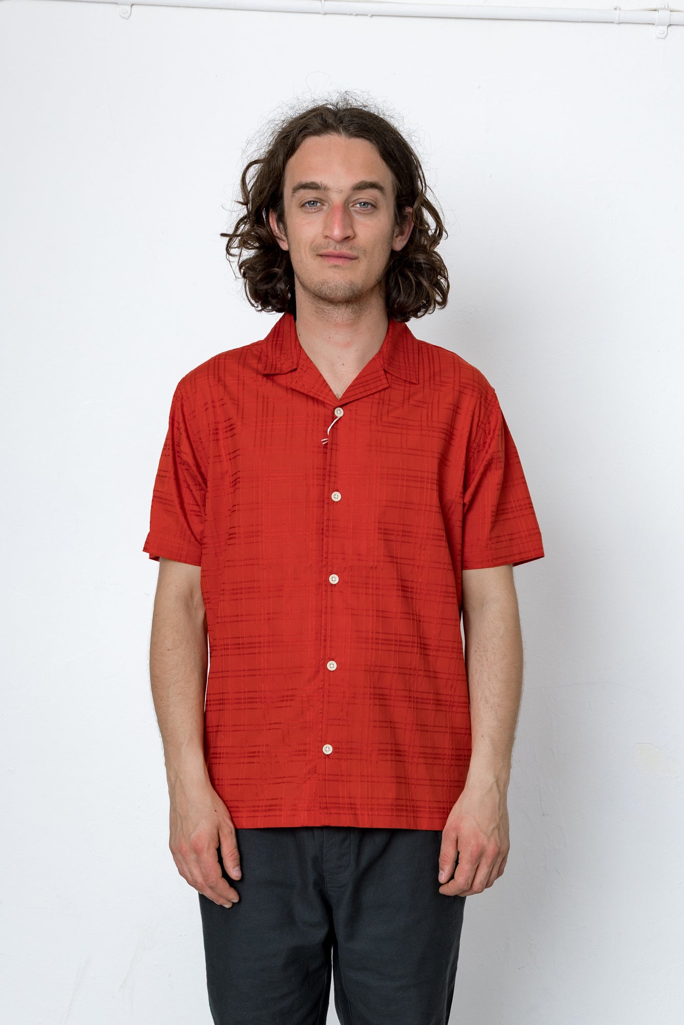 Man wearing a red short-sleeve shirt against a white background