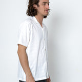 Man wearing a white shirt and dark pants against a plain white background