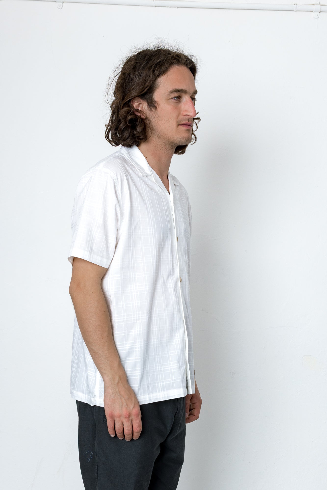 Man wearing a white shirt and dark pants against a plain white background