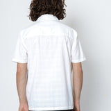 Person wearing a white checkered shirt against a plain background
