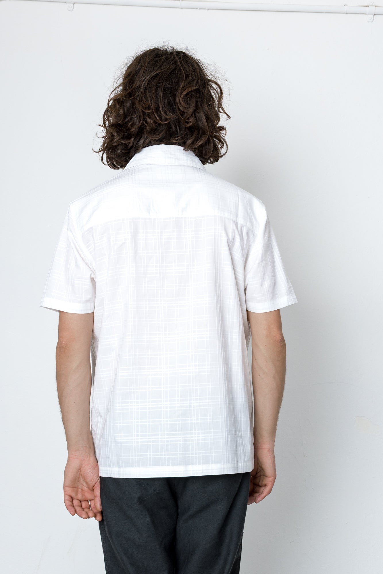 Person wearing a white checkered shirt against a plain background