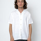 Man wearing a white shirt and dark pants against a white background