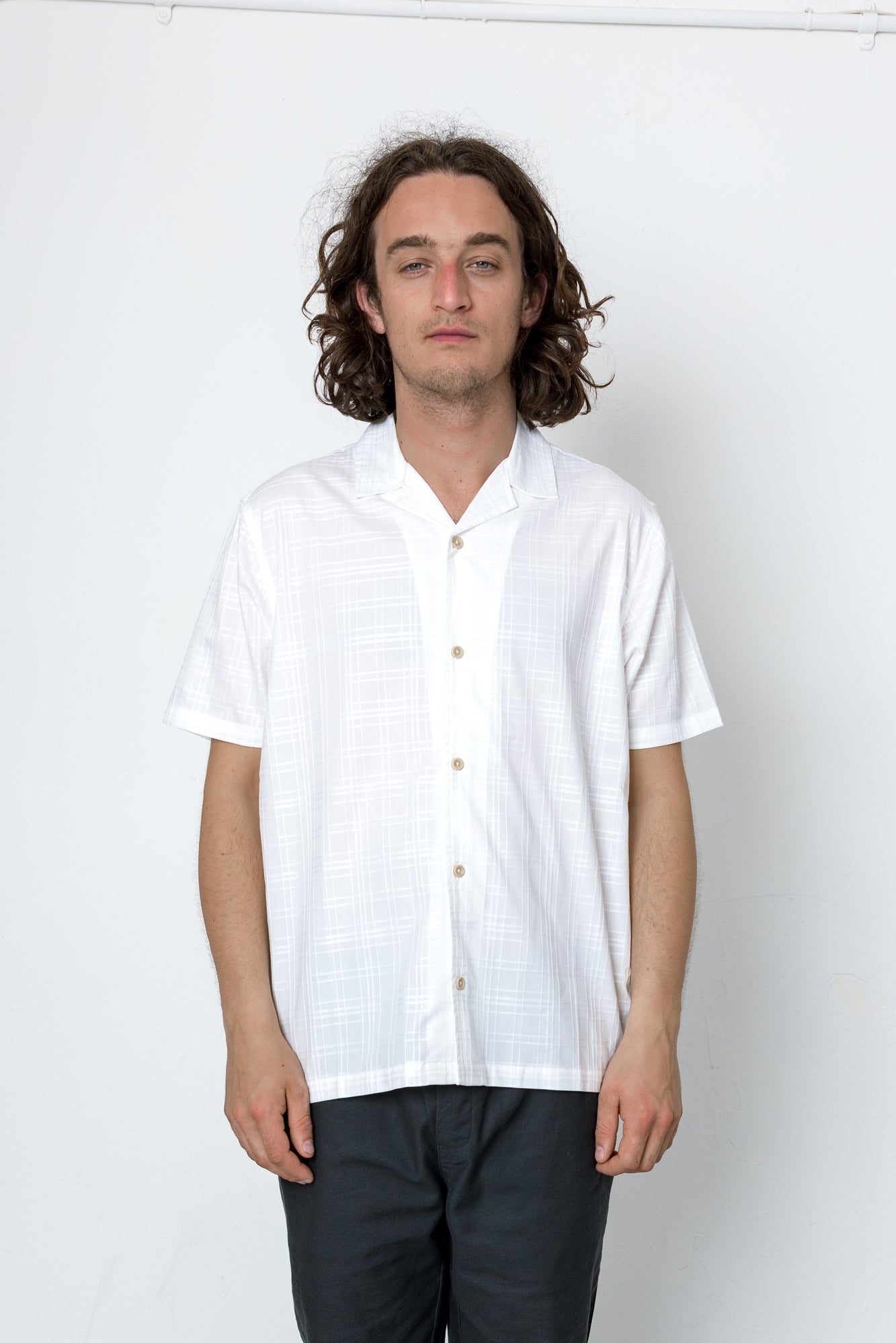 Man wearing a white shirt and dark pants against a white background