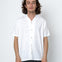 Man wearing a white shirt and dark pants against a white background