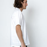 Man wearing a white t-shirt and dark pants against a plain white background
