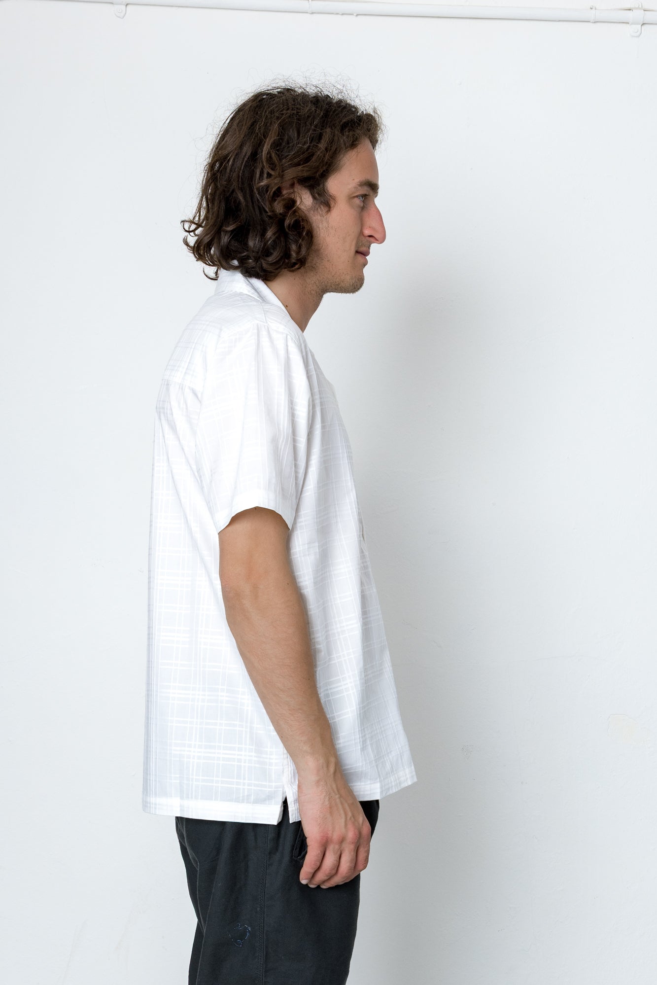 Man wearing a white t-shirt and dark pants against a plain white background