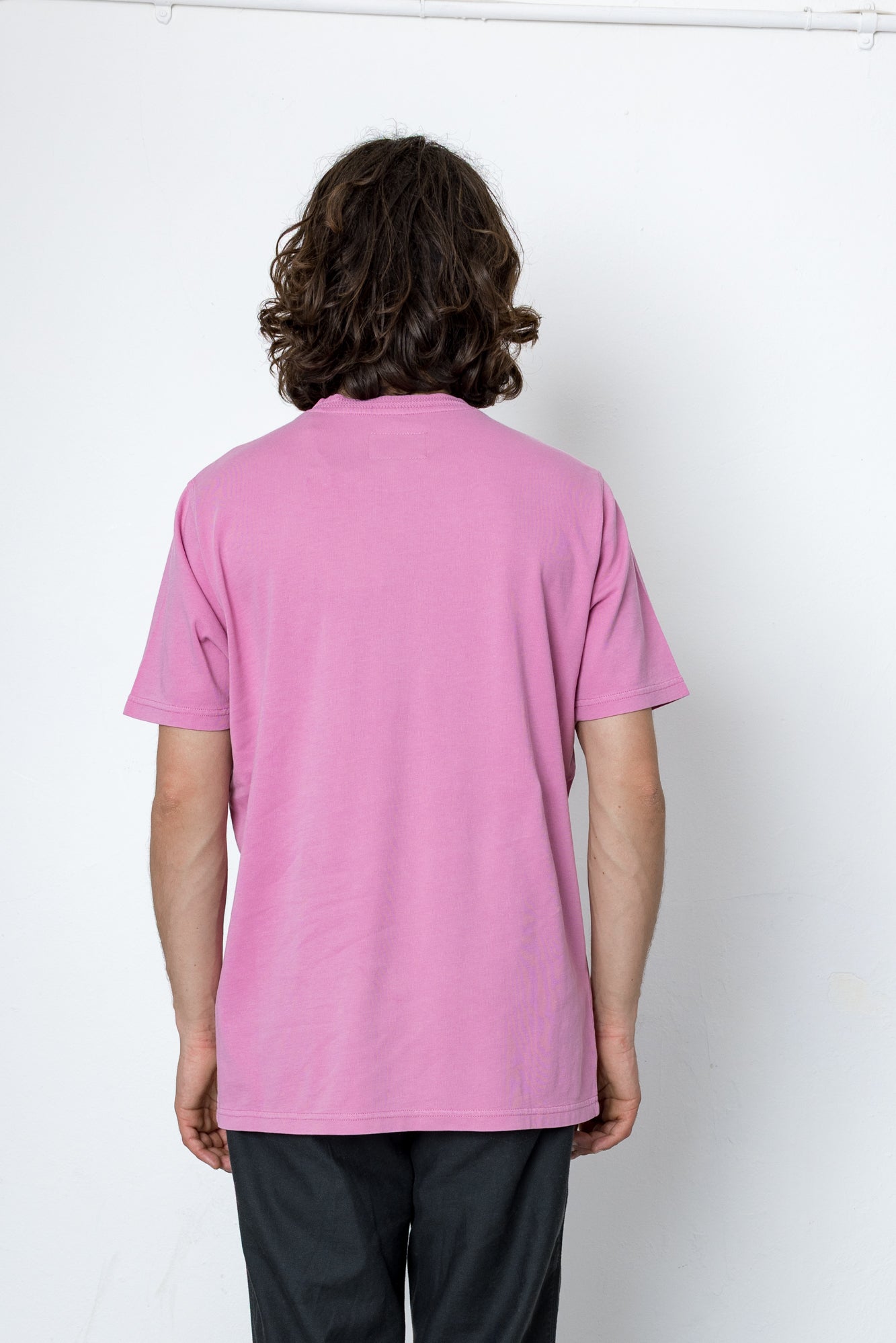Person wearing a pink t-shirt against a white background