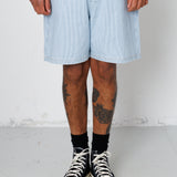 Person wearing light blue shorts and black high-top sneakers on a plain background