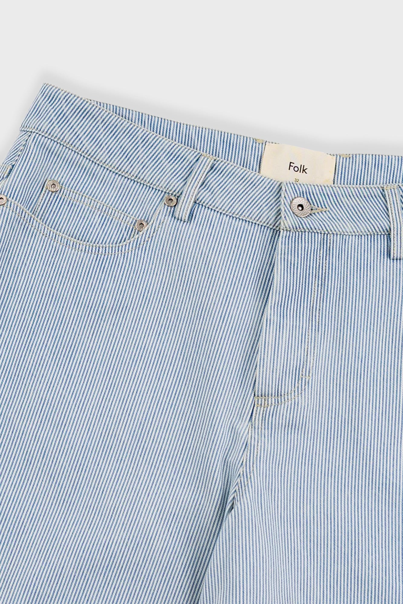 Close-up of light blue striped jeans with a brand label on a white background