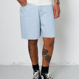 Person wearing light blue shorts and black high-top sneakers on a plain background