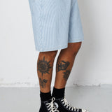 Person wearing light blue shorts and black high-top sneakers on a white background