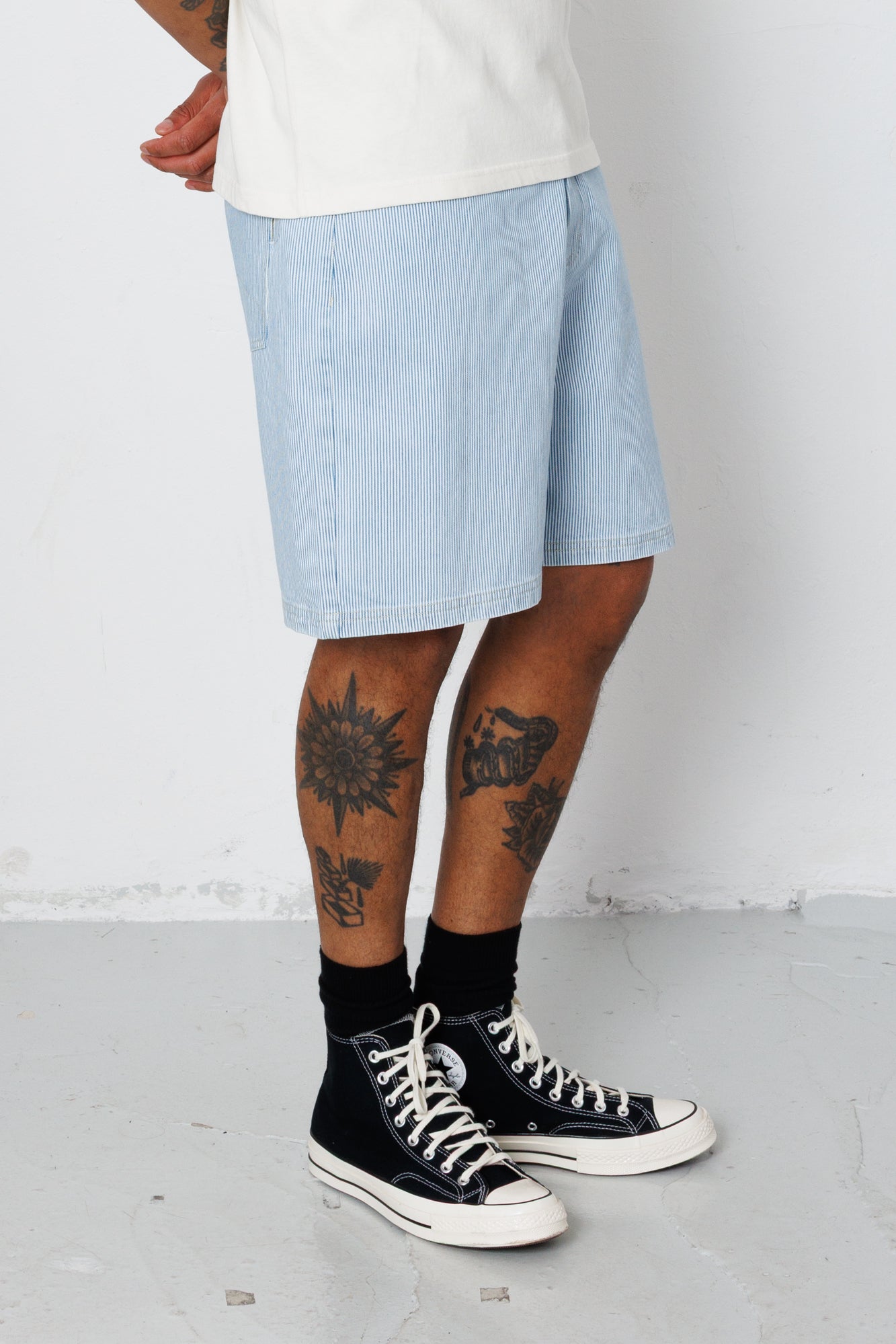 Person wearing light blue shorts and black high-top sneakers on a white background
