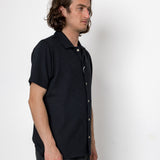 Man wearing a black shirt and pants against a white background